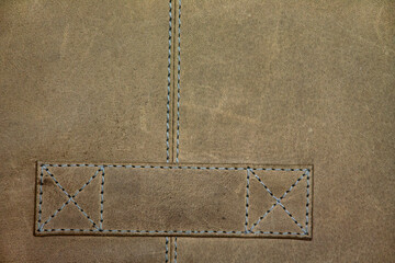 Texture of a beige natural leather with stitching