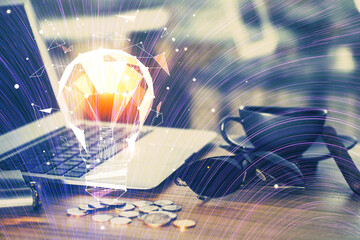 Computer on desktop in office with bulb icon hologram. Multi exposure. Concept of idea.