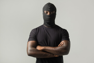 young african man in a black mask and a black t-shirt on a gray background