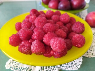 Red ripe respberries and wild plums on the table