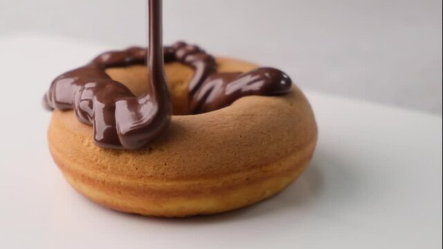 Chocolate icing is pouring on a donut