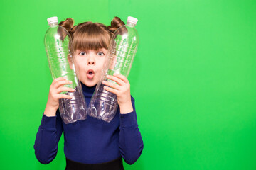 Photo of confused funny little girl holding plastic bottles and looking at camera isolated over green background