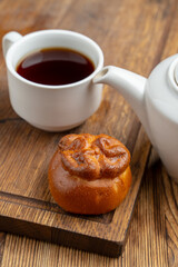 Russian piroshki on wooden table with black tea in a mug, close up