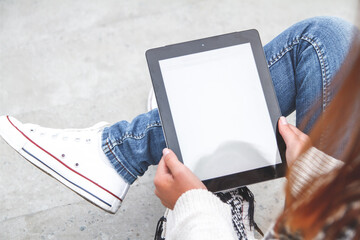 Young woman holding and using tablet with blank screen in hand top view.