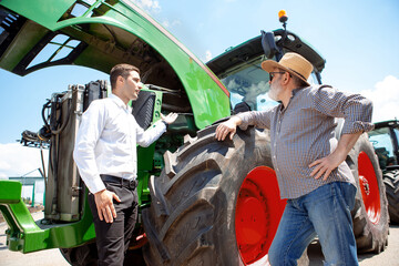 Professional farmer with a modern tractor, combine at a field in sunlight at work. Confident,...