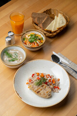 Pork cutlet with steamed pearl barley with soup and salad on wooden table