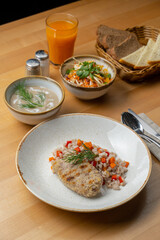 Lunch with chicken cutlet with pearl barley on wooden table in a cafe