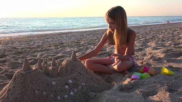 Kid Building Castle on Beach at Sunset, Child Playing Sands on Seaside, Blonde Girl Plays by Sea