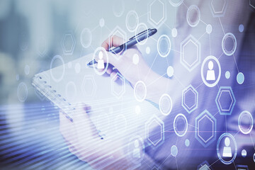 Social network theme hologram over hands taking notes background. Concept of global international people connect. Double exposure