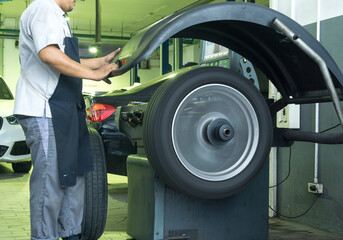 Fototapeta na wymiar Auto mechanic balances the car wheel on the wheel balancer machine in the Car garage.