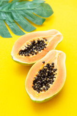 Papaya fruit isolated over yellow background. Exotic sweet fruit. Copy space.