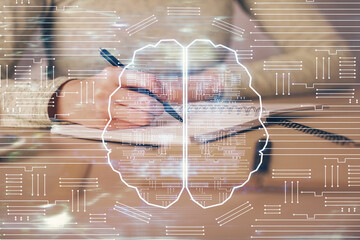 Double exposure of woman's writing hand on background with brain hud. Concept of learning.