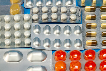 A pile of pills in blister packs close up. The blister pack is full of multi-colored tablets. A pack of full-color tablets. Pharmaceutical blister pack.