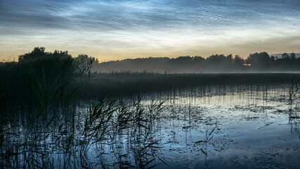 night landscape with white silver clouds over the lake, blurred foreground, charming cloud...