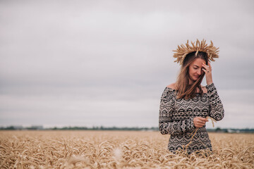 Naklejka na ściany i meble Beautiful, slender girl in a field of wheat against the rain sky