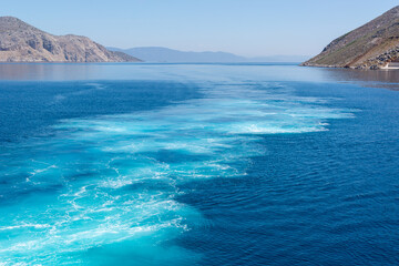 Naklejka premium Water trail foaming behind a ferry boat. Cyclades, Greece.