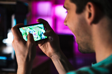 Image closeup of smiling man playing video game on mobile phone
