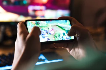 Tuinposter Image closeup of focused man playing video game on mobile phone © Drobot Dean