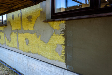 Applying construction glue layer on insulated wall for covering fiberglass reinforcing mesh on mineral wool.