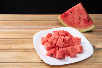 Watermelon in slice on a white crockery on wood, selective focus.