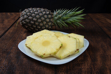 pineapple slices in a white crockery on a rustic wooden surface. Selective focus.