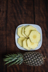 pineapple slices in a white crockery on a rustic wooden surface. tip view.