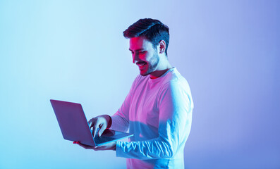 Work and play online. Happy guy holding laptop and typing