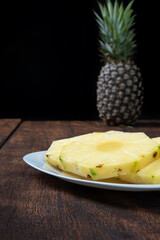 pineapple slices in a white crockery on a rustic wooden surface. Selective focus.