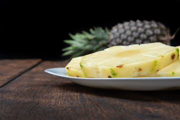 pineapple slices in a white crockery on a rustic wooden surface. Selective focus.
