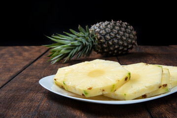 pineapple slices in a white crockery on a rustic wooden surface. Selective focus.