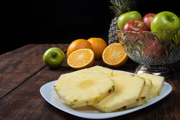 pineapple slices in a white crockery on a rustic wooden surface. Selective focus.