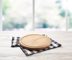 Empty pizza board and table cloth on wooden deck table with napkin. Kitchen background.