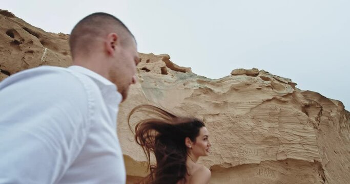Romantic couple running through the rocks and cliffs in the middle of the nature in front of the camera. 4k