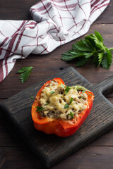 Stuffed sweet peppers with rice mushrooms and cheese with herbs. Baked halves of red peppers with filling. Dark wooden background. Copy space,
