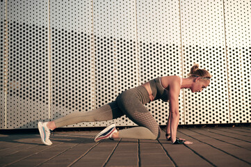 Strong fitness woman is doing mountain climber exercises in front of wall outdoor