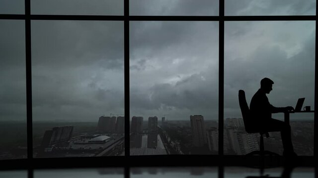 The businessman working at the table on the rainy sky background