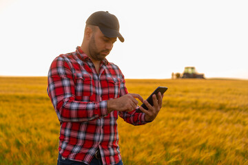 Naklejka na ściany i meble Farmer close-up holding and working on tablet in a wheat field. Copy space of the setting sun rays on horizon in rural meadow Close up nature photo Idea of a rich harvest 