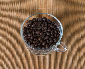 Roasted coffee beans in a transparent glass cup
