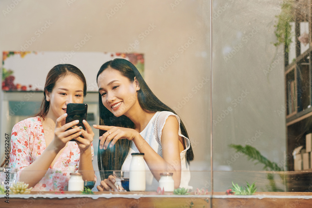 Sticker beautiful young vietnamese female friends checking photos they just made on smartphone