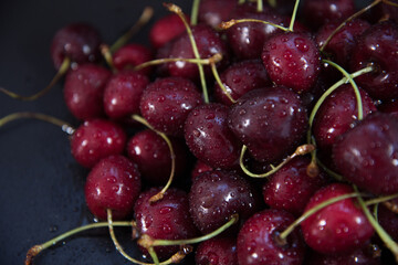 Red fresh cherries on a black background. Drop of water. Close up. The concept of freshness.