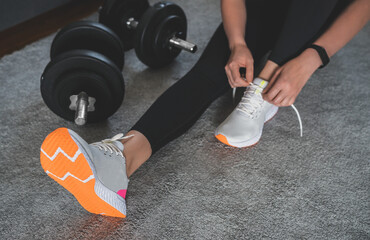 Woman tying shoelaces before exercise. Home fitness training concept.