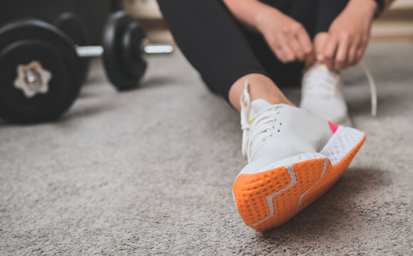Woman tying shoelaces before exercise. Home fitness training concept.