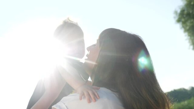 mom kiss newborn baby son holds in his arms playing in the park. mother day kid dream childhood happy family concept. parent play on hands with a little lifestyle boy son sunlight. people in the park
