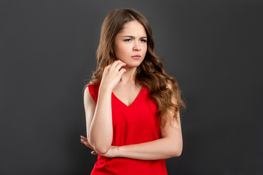 Skeptic woman portrait. Anxiety suspicion. Disturbed lady in red thinking isolated on gray background.
