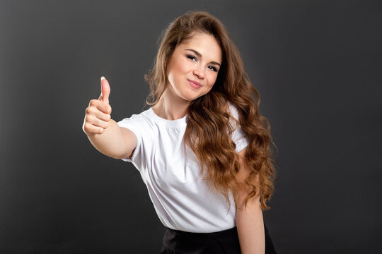 Like gesture. Perfect choice. Happy woman with thumb up isolated on gray background.