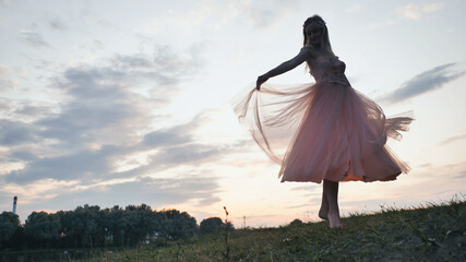 The girl in the dress swirls magically at sunset.