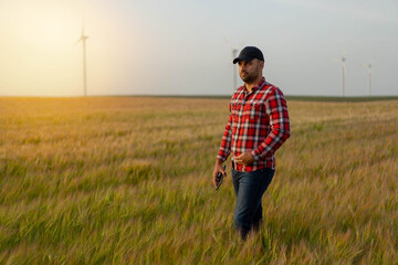 Naklejka na ściany i meble Portrait of Male farmer standing in wheat field with tablet inspecting crops.