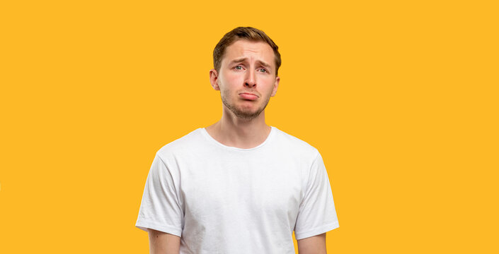 Depressed man portrait. Loneliness crisis. Unhappy guy in white t-shirt isolated on orange background.