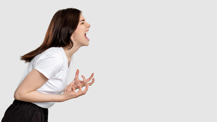 Mad woman portrait. Horror frustration. Insane lady isolated screaming at light empty space.