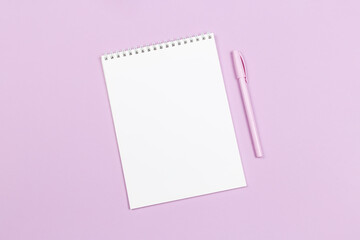 Notebook with blank page and pen on a violet pastel background.